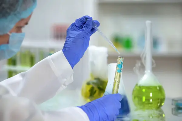 Naukowiec z probówką w dłoni w której znajduje się oleista substancja